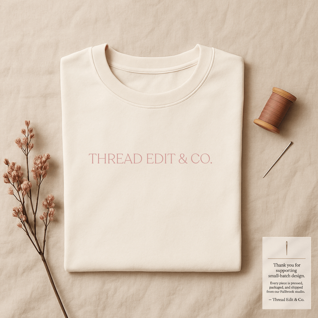 Secure Tee Deposit - Custom Design folded cream t-shirt with 'THREAD EDIT & CO.' text, styled with sewing accessories for mockup preview.